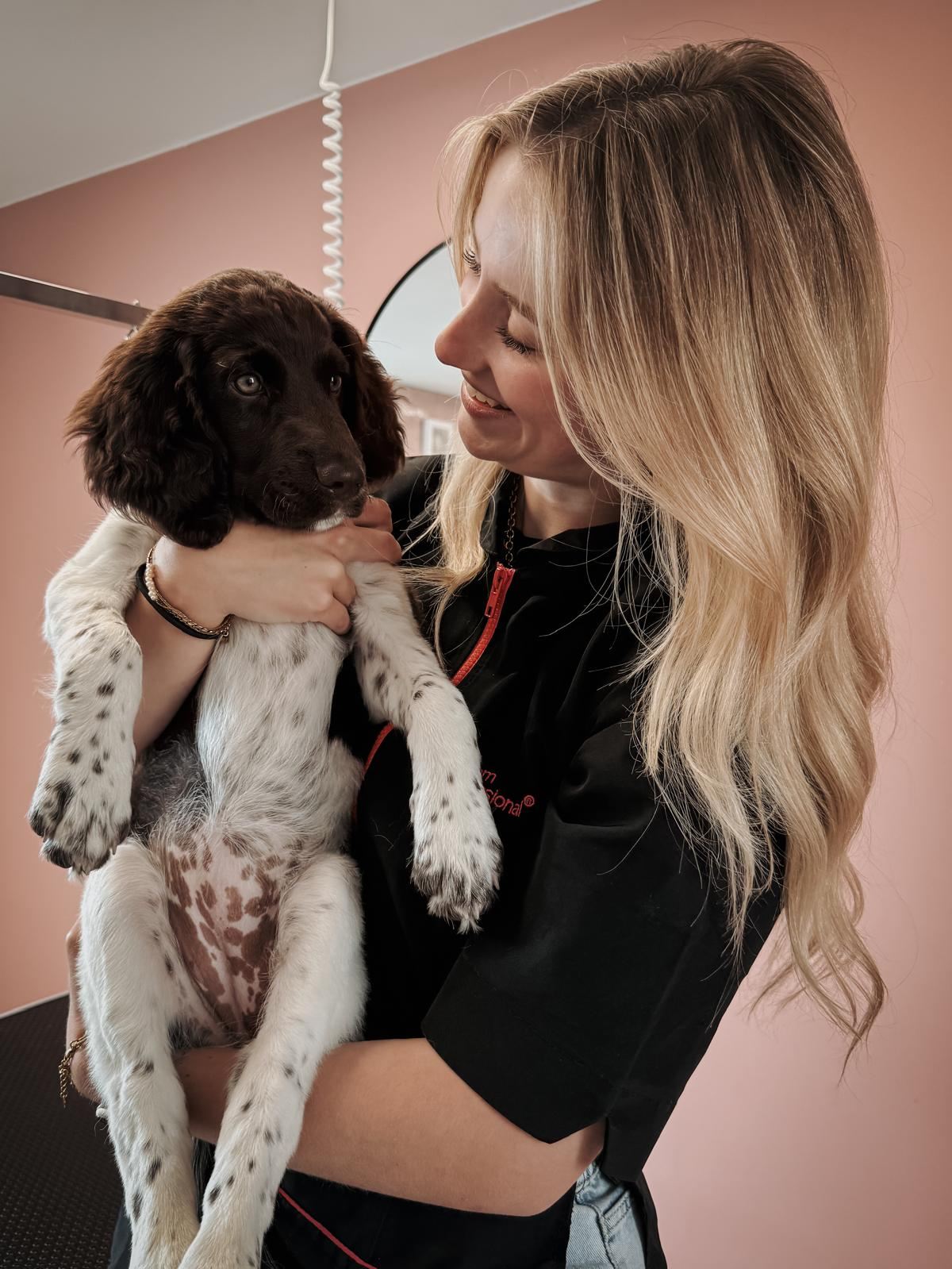 Tessa Theelen, hondentrimster van De Snuitstylist, knuffelt een puppy